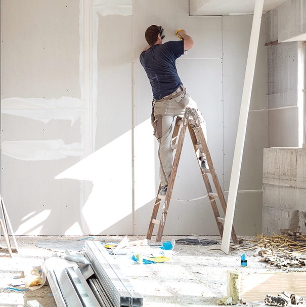 Bauarbeiter auf der Leiter. Renovierungsarbeiten an einer Wand, Baustelle